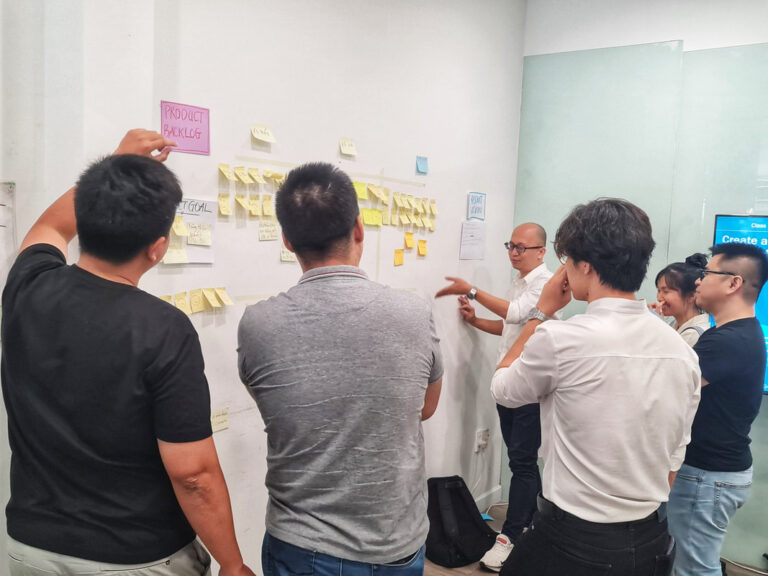 Học viên cùng trainer trao đổi bên tường dán ghi chú