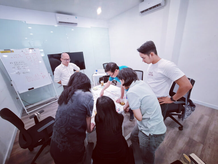 Trainer và học viên đứng quanh bàn